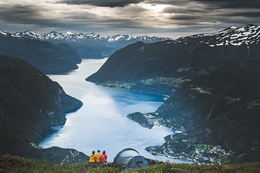 Girls camping in front of fjord in Sunnmore, Norway during sunset.