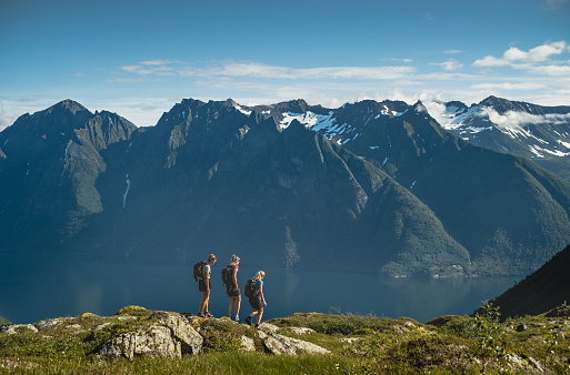 Girls hiking in front of fjord and mountain in Sunnmore, Norway during summer.