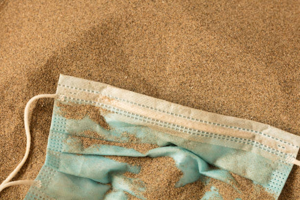 istock Waste during COVID-19. Scrapped to ocean coronavirus single-use face masks. Environmental and coastal plastic pollution. Trash on the beach that threatens the health of the oceans. 1276986077