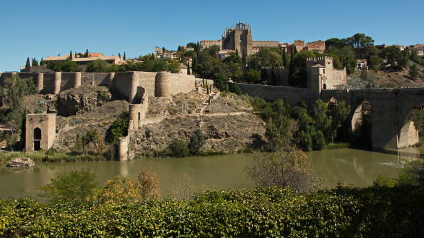 vista del ponte dell'alcantara sul fiume tago e sull'albergue castillo san servando a toledo, castiglia la mancia, spagna, europa - alcantara bridge foto e immagini stock