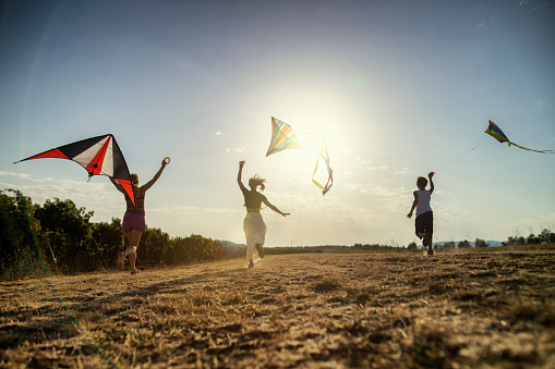 Family enjoying flying kites on a country road.\nNikon D850