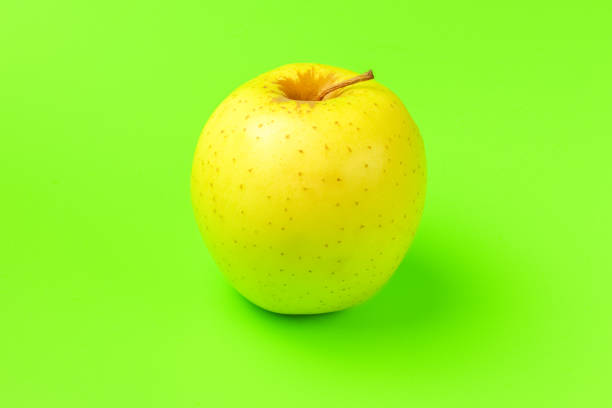 istock yellow Apple on a green background close-up.isolate 1276989090