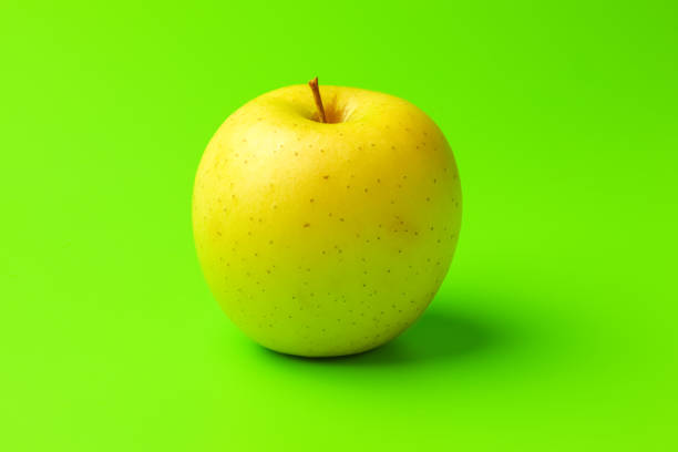 istock yellow Apple on a green background close-up.isolate 1276989555