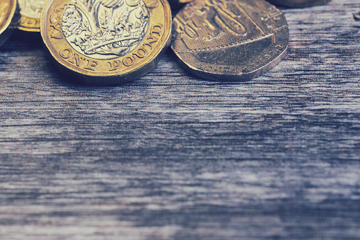 macro of British one pound coins on brown surface, with copy space