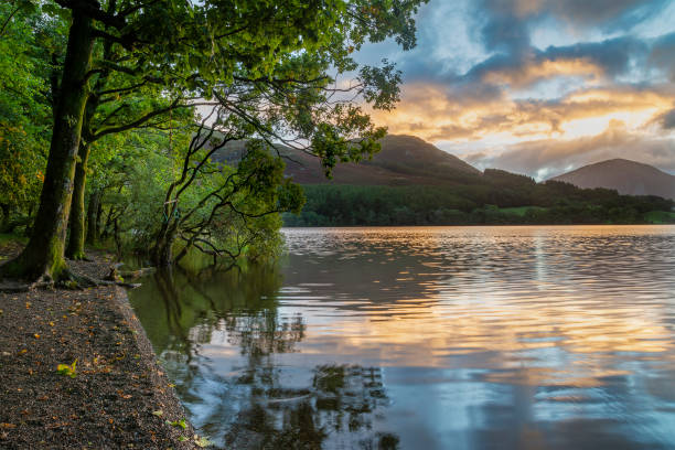 Beautiful sunrise landscape image looking across Loweswater in the Lake District towards Low Fell and Grasmere with vibrant sunrise sky breaking on the mountain peaks Stunning sunrise landscape image looking across Loweswater in the Lake District towards Low Fell and Grasmere with colorful sky breaking on the mountain peaks grasmere stock pictures, royalty-free photos & images