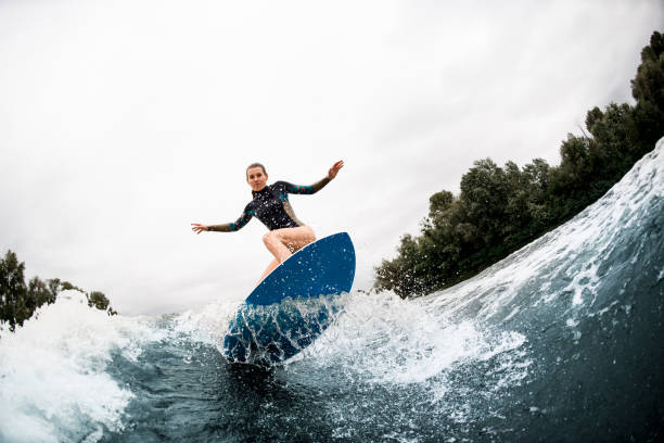 istock young woman stands with bent knees on surfboard and balanced on wave 1276990694