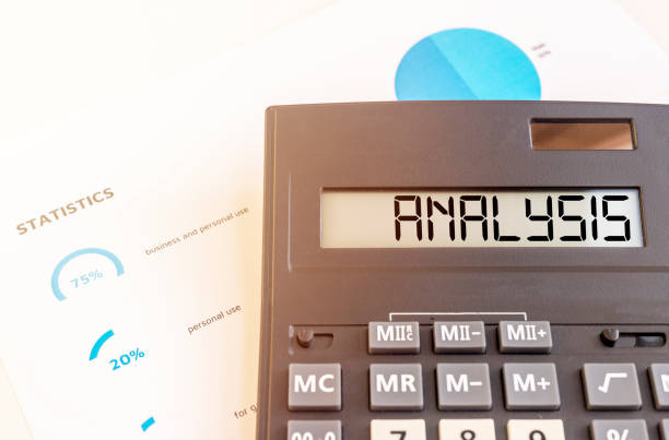 istock A calculator with the word analysis on the display close up and documents with marketing statistics in charts in blue color 1276991012