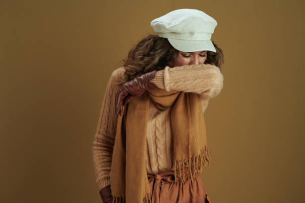 istock stylish woman sneezing into elbow on brown background 1276998101