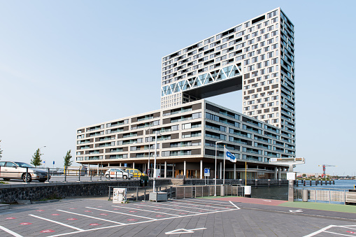 The Pontsteiger building on the south bank of the IJ waterway in Amsterdam, designed by Arons en Gelauff Architects and realised in 2019. The nickname of the apartment complex is the millionaire's building. The public transport ferries dock next to the building on the right side of the image.
