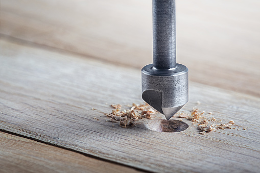 Countersink drill bit make sink in hole for screw in wooden plank.
