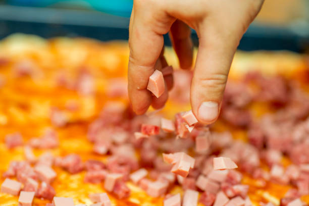 cooking pizza. hand woman cook puts salami slice on dough. making pizza - pizza sauces chef making imagens e fotografias de stock