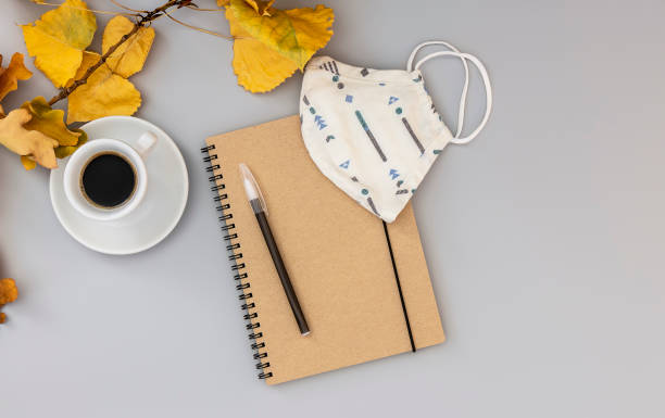 istock Workspace with notebook, mask, pen, autumn leaves, and coffee cup. 1277004710