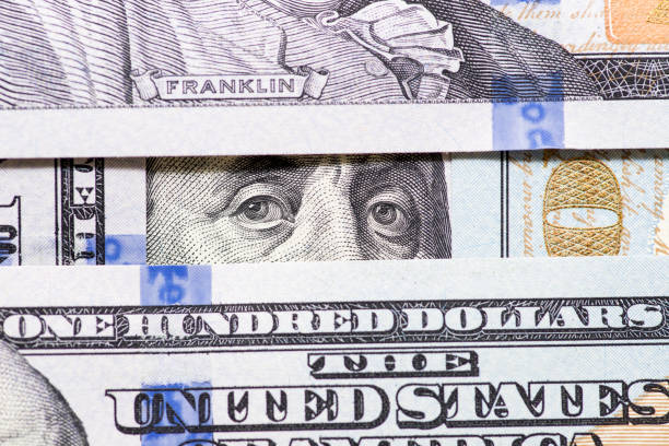 istock Benjamin Franklin's eyes between hundred dollar banknotes close-up. 100 dollar bill with only eyes of Benjamin Franklin 1277004880