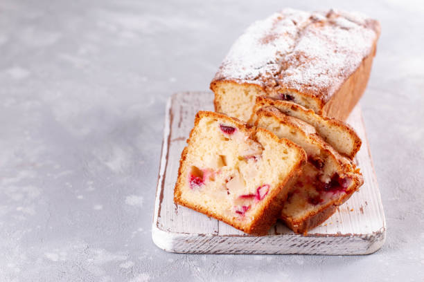 istock Sponge cake with plums and apples with powdered sugar on a light wooden board on a light background. Homemade baking, copy space 1277006219