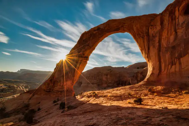 An image of Corona Arch in Utah with a sunburst