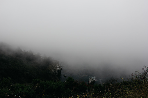 The view of the ocean on Big Sur road covered in fog.