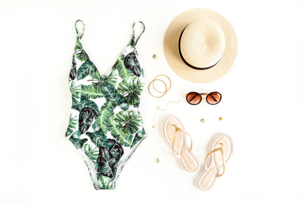 istock Woman's beach accessories: swimsuit with tropical print, straw hat on white background. Summer background 1277012916