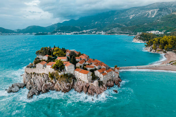 Sveti Stefan seen from above in the emerald waters of the Adriatic sea Luxury resort of Sveti Stefan seen from above in the emerald waters of the Adriatic sea and with Budva and mountains in the background. montenegro stock pictures, royalty-free photos & images