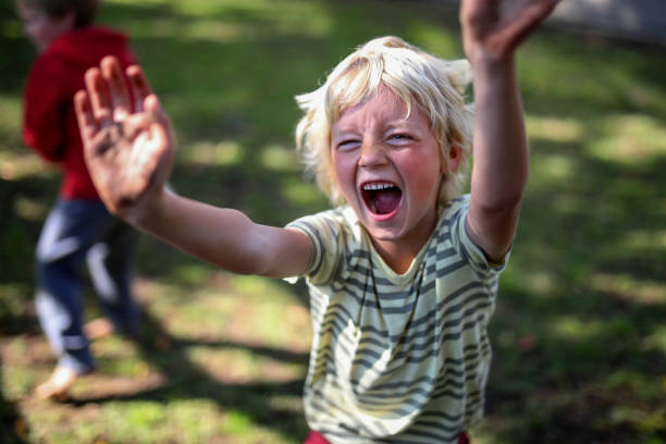 istock A young blond boy shouts at the camera with arms stretch out. 1277014591
