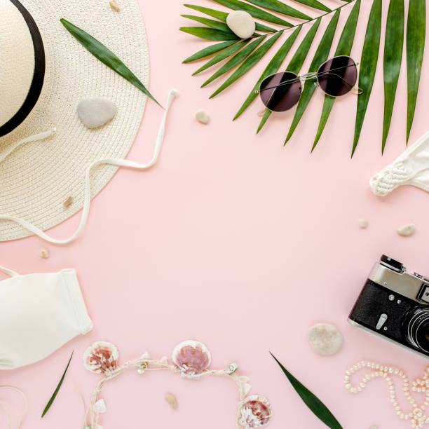 istock Feminine white swimsuit beach accessories, tropical palm leaf branches on pink background. Travel vacation concept. Summer background. Road frame set 1277015704