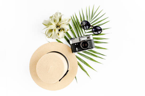 istock Flat lay traveler accessories on white background with retro camera, straw hat, sunglasses, and tropical palm leaf. Travel concept background 1277015924