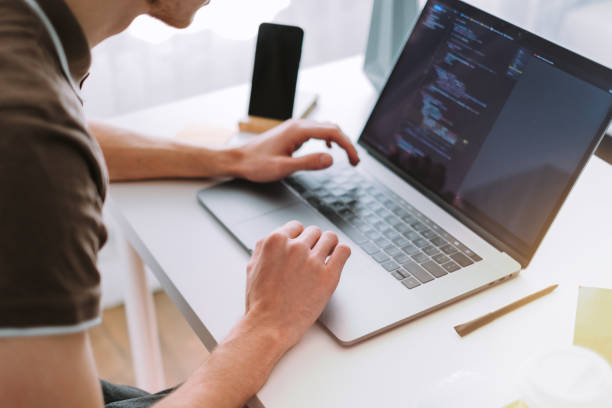 Young man mobile developer, programmer writes program code on a laptop stock photo