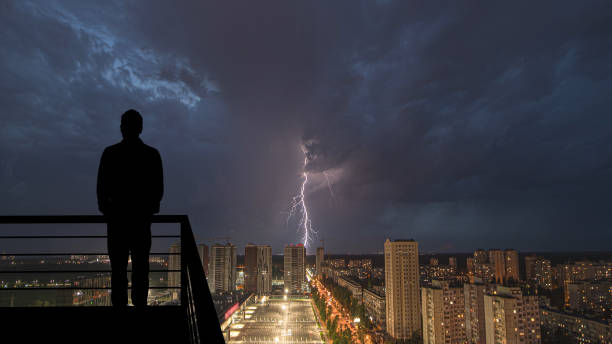 The man standing on the balcony on the raining background The man standing on the balcony on the raining background lightning tower stock pictures, royalty-free photos & images