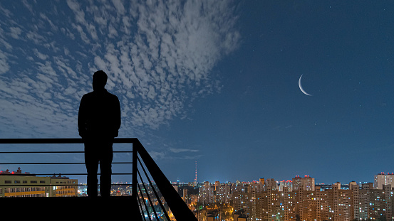 The man standing on the balcony on the night city background