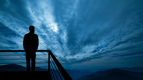 The man standing on the balcony on the mountains background