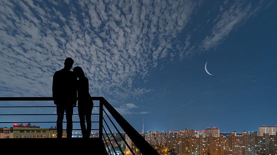 The romantic couple standing on the balcony on the night city background