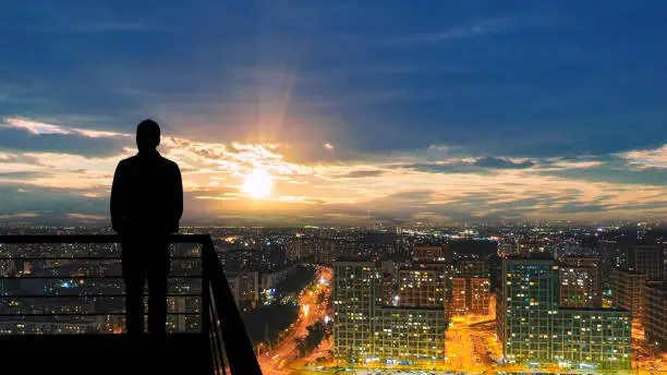 Photo of The man standing on the balcony on the big city background