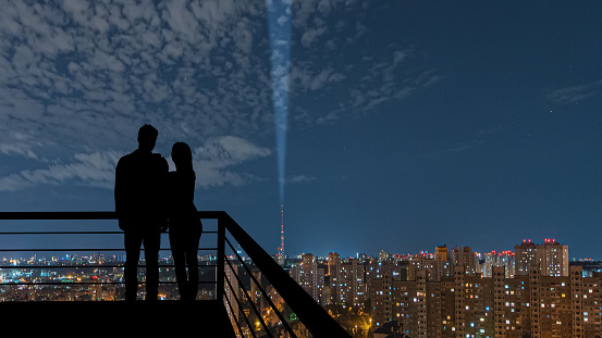 The romantic couple standing on the balcony on the night city background