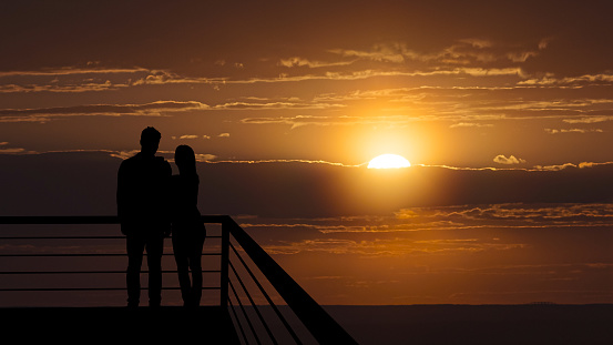 The romantic couple standing on the balcony on the beautiful sunset background