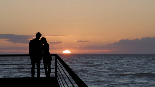 Photo of The romantic couple standing on the balcony on the beautiful seascape background
