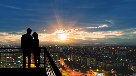 The romantic couple standing on the balcony on the cityscape background