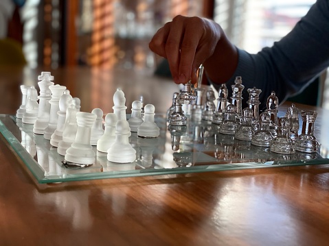 Close up of mans hand moving glass chess piece