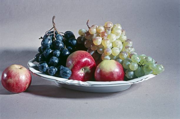 Extreme close-up of an apple and some grapes on a white plate
