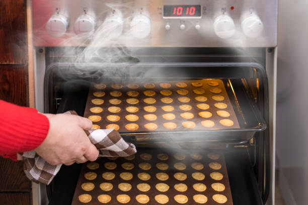 mão tirando biscoitos quentes de um forno de convecção fumegante de fogão de cozinha - full steam ahead - fotografias e filmes do acervo