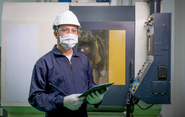 istock Factory worker man with mask hold the document also holds the document file and stand in front of operating machine 1277027332