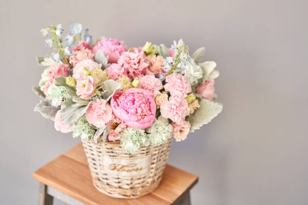 hermosa composición de flores un ramo en una cesta de mimbre. concepto floristería. colores primaverales - wicker basket store gift shop fotografías e imágenes de stock