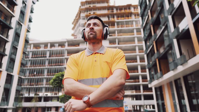 Man wearing safety equipment hearing protection. Worker wearing noise cancelling ear defenders or ear muffs. Construction builder puts on protect ears with headphones. Taking care safety during work