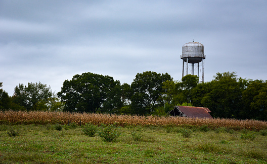 A water tower stands above a field with a barn roof seen below.