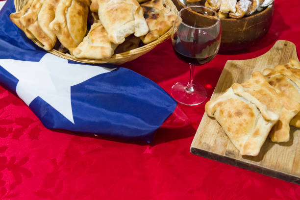 September 18th, Chilean food Independence Day Concept, Fiestas patrias. Chilean typical menu on independence day party, September 18th. Beef rustic empanadas, Pebre (Tomatoes sauce with white onions), Pastel de Choclo (Corn Pie), Calzones Rotos (Dessert) and tipical play trompo and a Chilean Flag around the table.