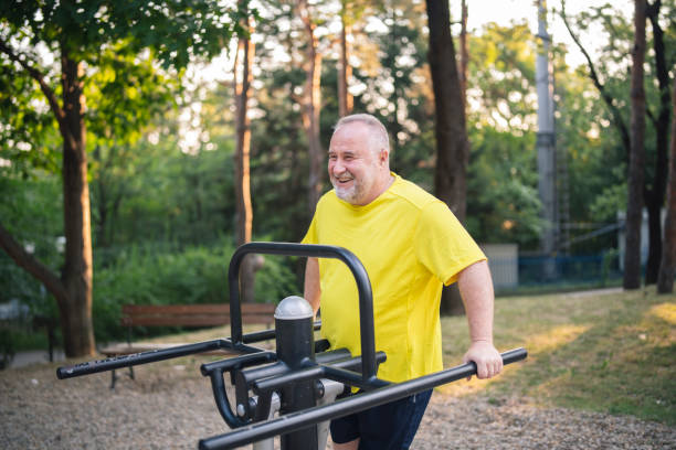 старший мужчина использует парк фитнес-оборудование для тренировки снаружи - exercise equipment exercising dieting sport стоковые фото и изображения