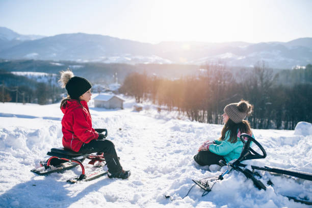 istock Two Little Kids Are Playing With Their Slide In The Snow 1277041237