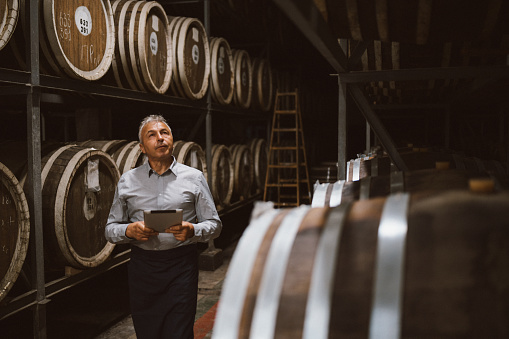 Senior distiller is examining the whiskey barrels