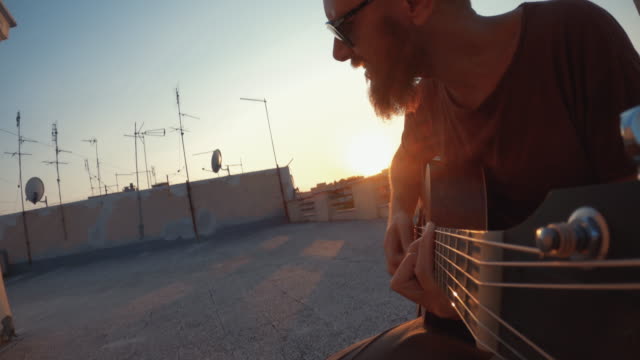 Man playing acoustic guitar on the terrace during Covid-19 lockdown