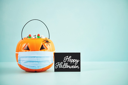 Halloween background with Jack O'lantern filled with candy wearing a face mask