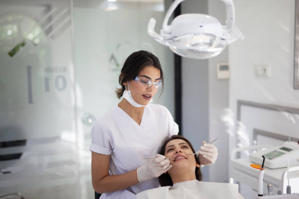 jeune femme ayant un examen dentaire - dental assistent photos et images de collection