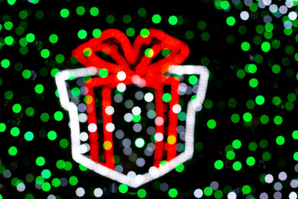 Bokeh Christmas gift box with a large red bow from color lights on at night christmas tree. party lights. New Year Celebration